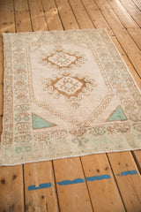 Angled view of a distressed Oushak rug highlighting its partial prayer design and double bronze medallions.