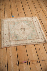 Distressed vintage Oushak rug corner showing even wear, seafoam green field, and subtle bird-like border.