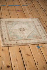 Distressed vintage Oushak rug corner, pale rose and seafoam green bird-like border motifs.