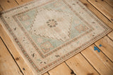 Vintage distressed Oushak rug corner with intact selvage and muted seafoam green floral border.