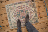 Distressed Oushak rug corner, geometric palmette motifs in pink, blue, and ivory, with boot detail.