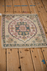 Distressed Oushak rug corner showing pink palmettes and blue meandering vine border.