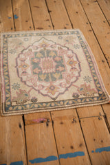 Corner of distressed Oushak rug showing pink palmette, blue vine border, soft pile wear.