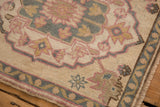 Distressed vintage Oushak rug corner featuring pale pink, blue, gold palmette and vine motifs.