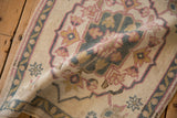 Textured distressed Oushak rug pile showing muted pink, blue, gold leaf and vine.