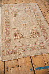Distressed vintage Oushak rug corner with hand-knotted pile, fringe, and beige geometric motifs.