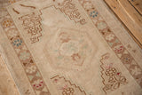 Distressed Oushak rug corner showing stepped spandrel and geometric blossoms in muted tones.