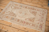 Distressed vintage Oushak rug corner showing worn geometric border and fringed edge.