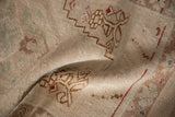 Folded distressed Oushak rug displaying worn beige pile and brown geometric pattern.