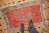 Worn, low-pile texture of a distressed Oushak rug with a red field and sage green border.