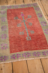 Vintage Oushak rug's red tree-of-life field and sage geometric border, seen from an angle.