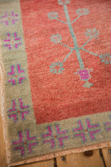Corner view of a vintage Oushak's worn pile, showing the sage and fuchsia quatrefoil border.