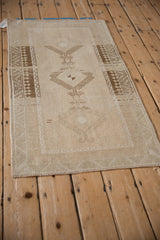 Angled view of a vintage Malatya rug showing the geometric triple medallion and its low, distressed pile.