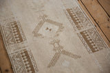Ram's horn finial and pawn design motif in pale coffee brown on a distressed rug.