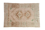 Vintage distressed Oushak rug with a double medallion prayer design in muted cream, brown, and seafoam green.