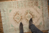 A person's view showing the scale and soft, distressed texture of a vintage Turkish Oushak rug.