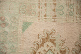 Evenly worn knot heads on a vintage Oushak with seafoam green and coffee brown geometric motifs.