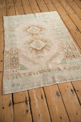 Angled view of a vintage distressed Turkish Oushak rug highlighting its pale, time-softened color palette.