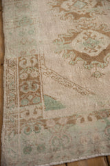 Evenly worn, low pile of a vintage Oushak rug with seafoam green and coffee brown motifs.