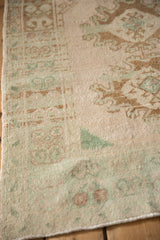 Angled detail of a distressed Oushak rug's even wear and intact side cord selvage.