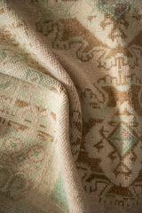 Close-up of a vintage Oushak rug's low pile, showing hand-knotted texture in seafoam and coffee.