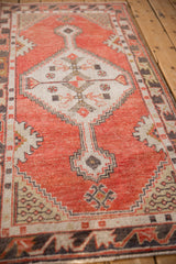 Distressed brick red field texture and ivory stepped medallion contour on the Oushak runner.