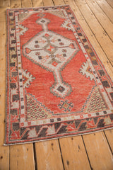 Distressed brick red field, ivory stepped spandrel, and charcoal vine border of vintage Oushak runner.