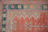 Corner detail of a distressed Oushak rug showing a teal border and cantaloupe melon mehrab.