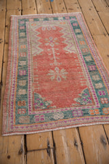 Angled view of a distressed Oushak rug's low pile and melon, teal, and magenta palette.
