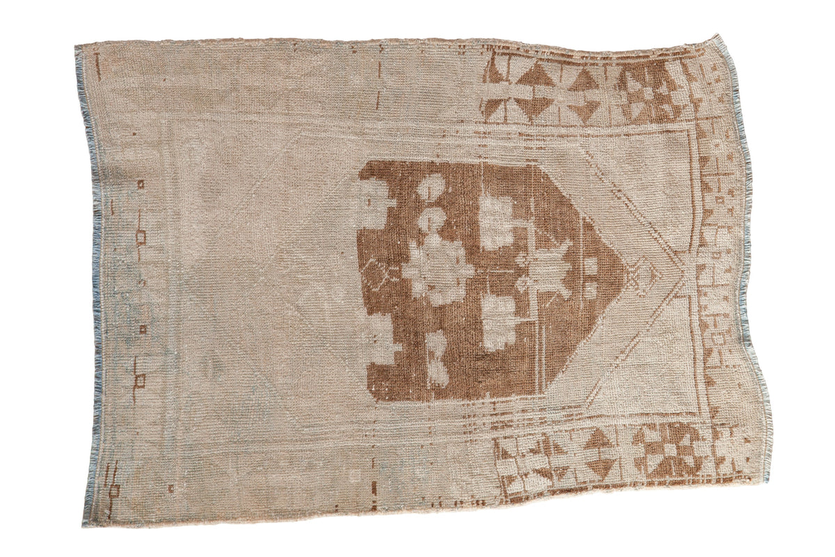 Vintage distressed Oushak rug with a hexagonal brown medallion on an ivory field with heavy abrashes.