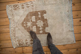 A distressed vintage Oushak rug with visible wear to the knot heads and a soft, muted palette.