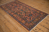 Angled view of a vintage Mehrivan rug's sprawling floral pattern on a dusty rose ground.