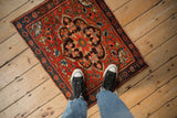 Antique Persian Farahan Sarouk bag face rug with a red floral pattern, shown to scale on a floor.