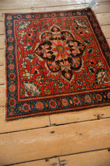 Antique Persian rug from an angle, showcasing its large-scale scalloped medallion and floral field.