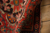 Folded view of an antique Farahan Sarouk rug's detailed floral border and rich, textured pile.