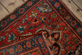 Folded corner of an antique Farahan Sarouk rug reveals its hand-knotted foundation and pile.