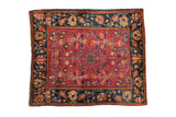 Antique Farahan Sarouk rug with a floral pinwheel medallion on a cochineal field and a navy palmette border.