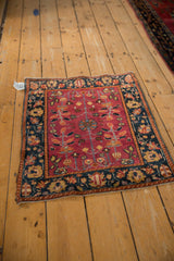 Antique Farahan Sarouk rug at an angle, displaying its rich cochineal field and detailed navy border.