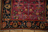 Detail of the navy border's palmette design and cochineal field on a collector Farahan Sarouk rug.