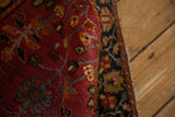 Angled view of the soft, cochineal red pile and navy floral border of a Farahan Sarouk rug.
