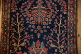 Antique Persian Farahan Sarouk rug with deep navy field, blossomed floral patterns, and serpent border.