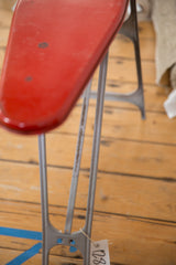 Close-up of the weathered metal frame and folding legs of a vintage ironing board.