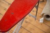 Vintage patina and surface scratches on the ironing board's red metal top.