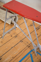 Side profile of the vintage ironing board's folding metal frame, highlighting its age-worn patina.