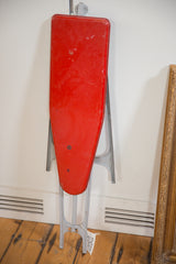 Vintage children's ironing board in its folded, upright position for storage.