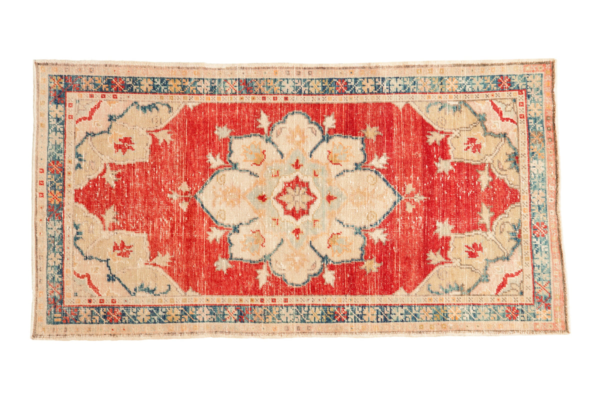 Vintage distressed Oushak rug with a starburst medallion on a cherry red field and a dusty teal geometric border.