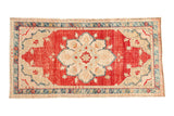 Vintage distressed Oushak rug with a starburst medallion on a cherry red field and a dusty teal geometric border.