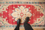 A person's view standing on a distressed Oushak rug, showing its texture and scale.