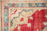Corner spandrel of a distressed Oushak rug with low pile and dusty teal motifs.