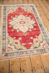 Angled perspective on a distressed vintage Oushak runner's cherry red field and beige pattern.